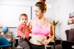 Young mother in sportswear measuring her waist worried about her weight after the child birth 300x200