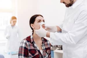 Nice serious woman having a medical dressing on her nose 300x200